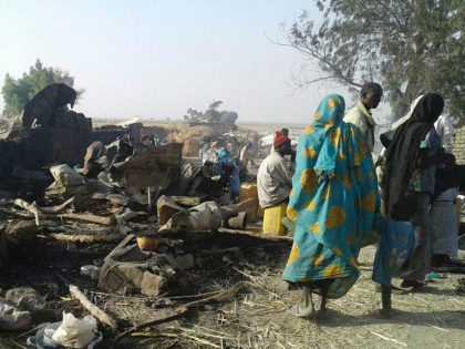 People walk at the site after a bombing attack of an internally displaced persons camp in