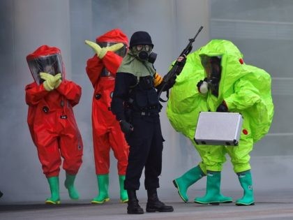 South Korean rescue members wearing chemical protective suits gesture as an armed policema