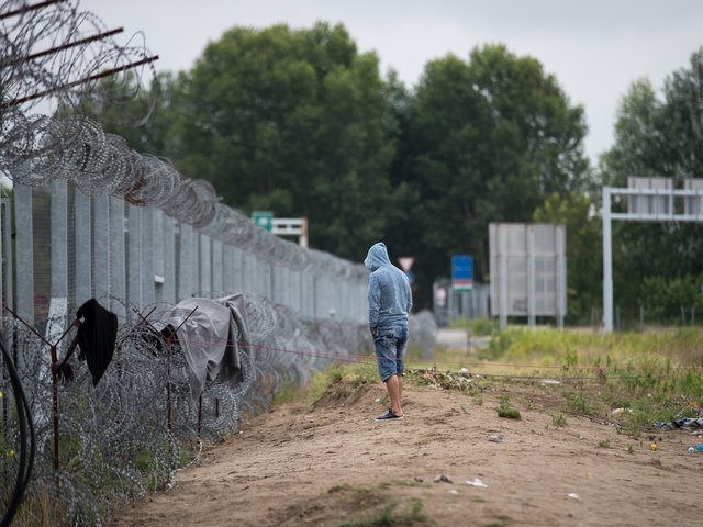 HORGOS, SERBIA - JULY 17: A man stands besides the border fence close to the E75 Horgas b