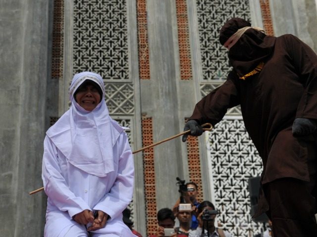 A religious officer canes an Acehnese youth onstage as punishment for dating outside of ma