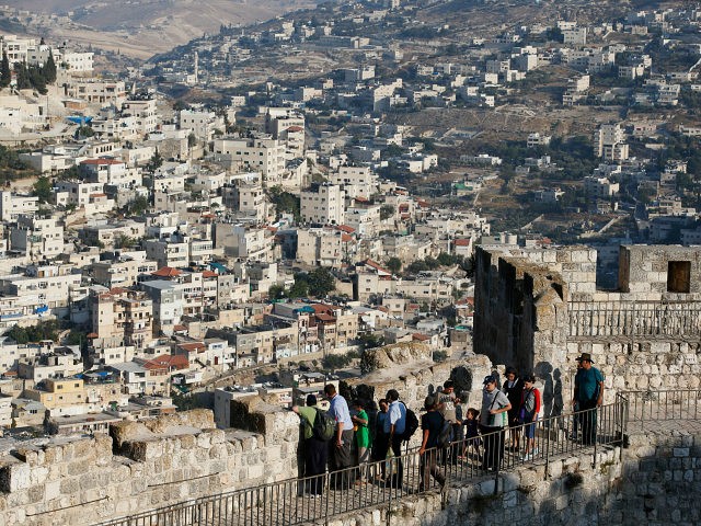 Arab neighbourhoods in East Jerusalem are seen in the background as tourists walk atop a w