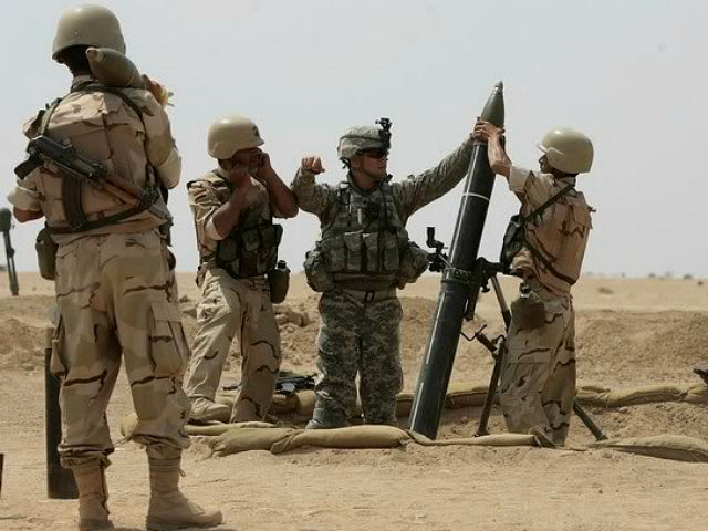 A US military adviser helps soldiers from the 17th Iraqi army brigade load a mortar during