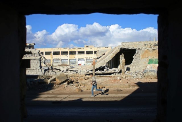 A Syrian boy runs past the rubble of destroyed buildings in the rebel-held area of Daraa,