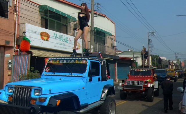 Pole dancers perform on top of jeeps during the funeral procession of former Chiayi City c