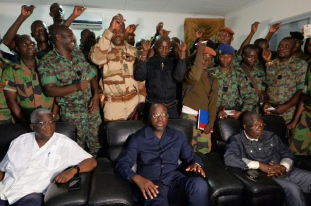 A delegation of mutinous soldiers stand behind Ivory Coast's defence minister Alain-Richar