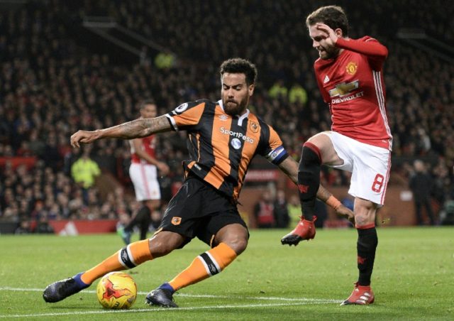 Hull City's midfielder Tom Huddlestone (L) clears the ball from the path of Manchester Uni