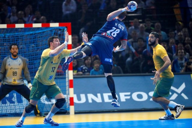 France's right back Valentin Porte (C) jumps to shoot next to Brazil's pivot Alexandro Poz