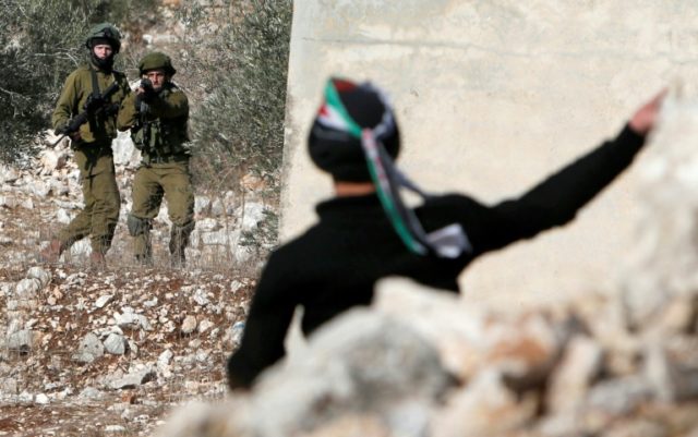 A Palestinian protester throws stones towards Israeli security forces during clashes near