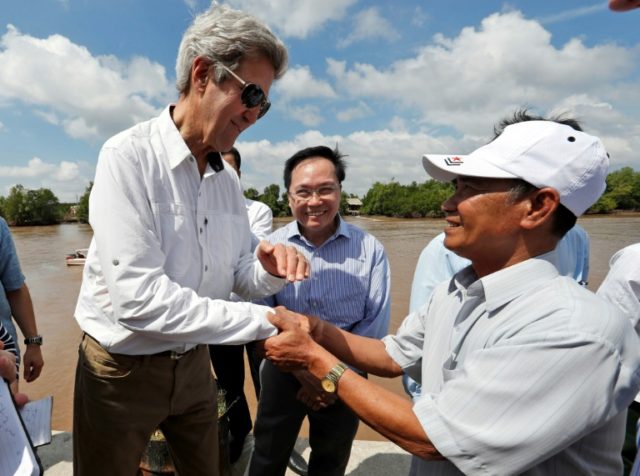 US Secretary of State John Kerry (L) shakes hands with Vo Ban Tam, 70, who was a member of