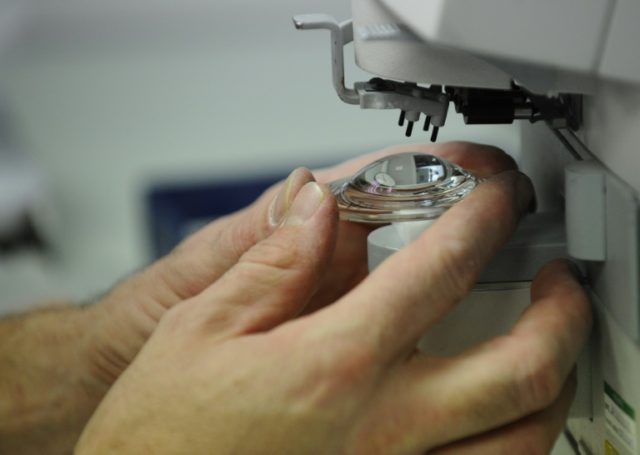 An employee works on an ophthalmic lens at 'special glasses' laboratory of the Essilor fac