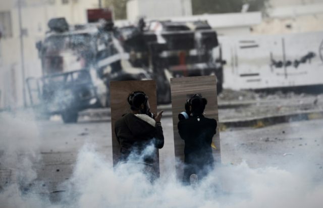 Bahraini protesters are seen taking cover during a confrontation with police after a demon