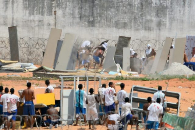 Prisoners use makeshift shields as riot police fire rubber bullets during a rebellion at t