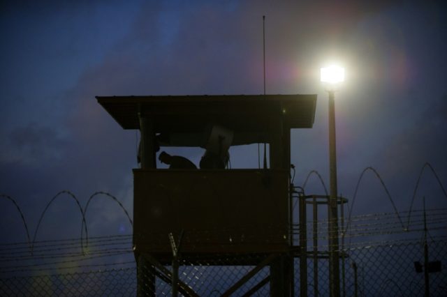 A member of the US military mans the guard post before sunrise at Camp Delta, part of the