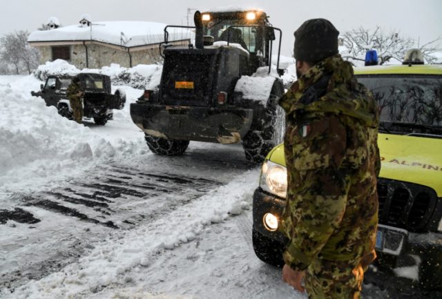 An Italian soldier takes part in an operation to clear snow from a street in Arigno, near