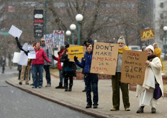 Demonstartors hold signs in the snow during a rally in support of the Affordable Care Act