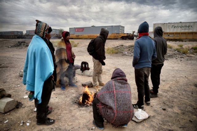 Honduran migrants warm themselves next to a campfire near train tracks in Sonora state, Me