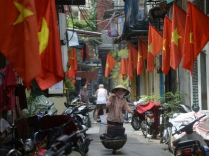 A street vendor walks past rows of Vietnamese national flags hung in outside homes in down