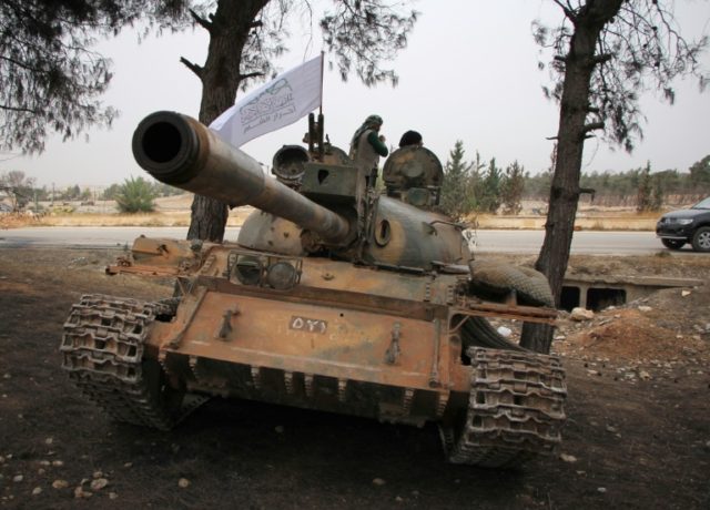 Syrian rebel fighters from the Jaish al-Fatah (or Army of Conquest) stand on a T-55 tank a