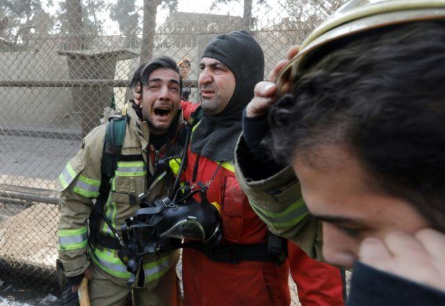A firefighter consoles his comrade after the collapse of the 15-storey Plasco building in