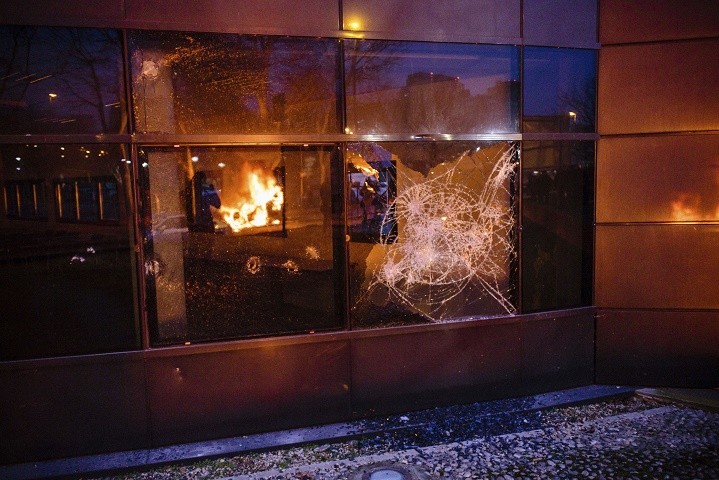 A fire set up by protestors is reflected in a broken window after a demonstration in Bobigny outside Paris, Saturday, Feb. 11, 2017. A peaceful demonstration protesting the alleged rape of a black youth by police has degenerated, with small groups setting at least one vehicle afire and throwing projectiles at police. (AP Photo/Aurelien Morissard)