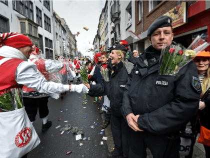 Police get flowers by revelers while they secure the traditional carnival parade in Cologne, western Germany, Monday, Feb. 8, 2016. Many carnival parades in Germany were cancelled because of stormy weather. The foolish street spectacle in Cologne, normally watched by hundreds of thousands of people, is the highlight in Germany's …