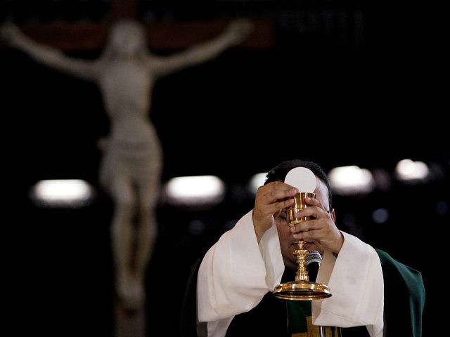 In this May 29, 2013 photo, a priest blesses the wine and bread as he celebrates Mass at a Catholic church in Caracas, Venezuela. Church officials say food shortages and foreign exchange restrictions are causing a lack of ingredients needed to celebrate Mass: altar wine as well as wheat to …