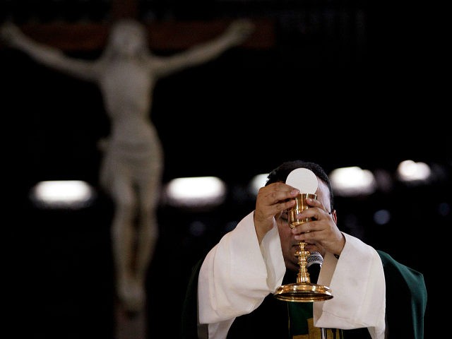 In this May 29, 2013 photo, a priest blesses the wine and bread as he celebrates Mass at a