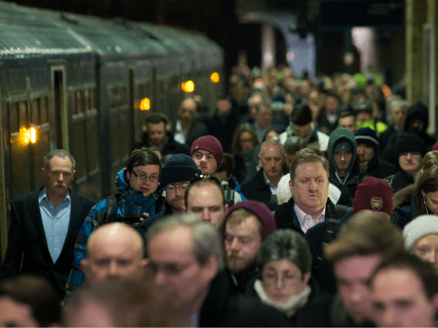 Commuters walk alongside train carriages after arriving at King's Cross railway stati