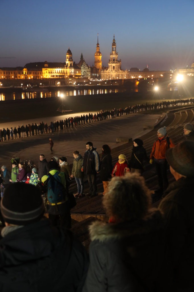 DRESDEN, GERMANY - FEBRUARY 13: People form a human chain across from the rebuilt, historic city center to both commemorate the 72nd anniversary of the Dresden firebombing and to make a statement against right-wing groups who seek to use the anniversary for political ends on February 13, 2017 in Dresden, Germany. In the February 13-14, 1945, attack on Dresden Allied bombers obliterated the city center in a carefully planned firestorm that killed at least 25,000 people only a few months before the end of World War II. (Photo by Sean Gallup/Getty Images)
