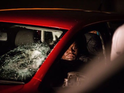 A man sits in his damaged car after it was smashed by residents of the worker's hostel in Jeppe's Town neighbourhood of Johannesburg on February 26, 2017. Violence flared up again around the restive hostels of Jeppe's Town, theatre of violence during the xenophobic violence of 2015. Shops and homes …