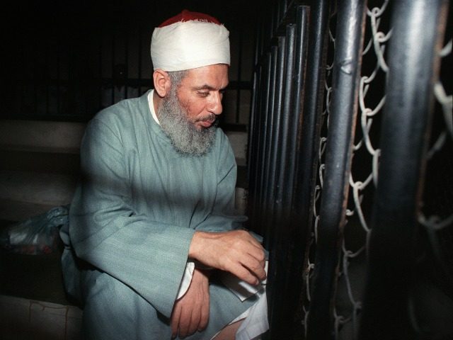 Blind Sheikh Omar Abdel Rahman sits and prays inside an iron cage at the opening of court
