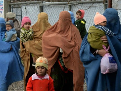 Afghan refugee women carry their children as they arrive to update their family data at th