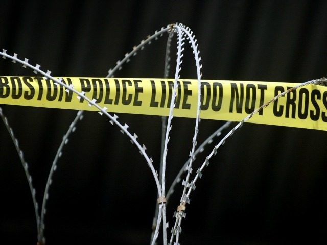 Concertina wire, and for added emphasis yellow police tape, top a fence surrounding an are