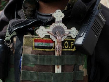 Rami Raad, a fighter with Shiite Popular Mobilization Forces, placing a cross and Iraqi fl