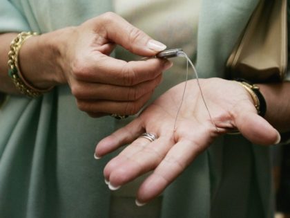 Queen Silvia of Sweden holds a cochlear implant in her hands during a visit to the Sydney