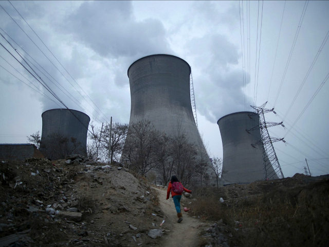 A girl makes her way to her house which locates next to cooling towers of coal-fired power