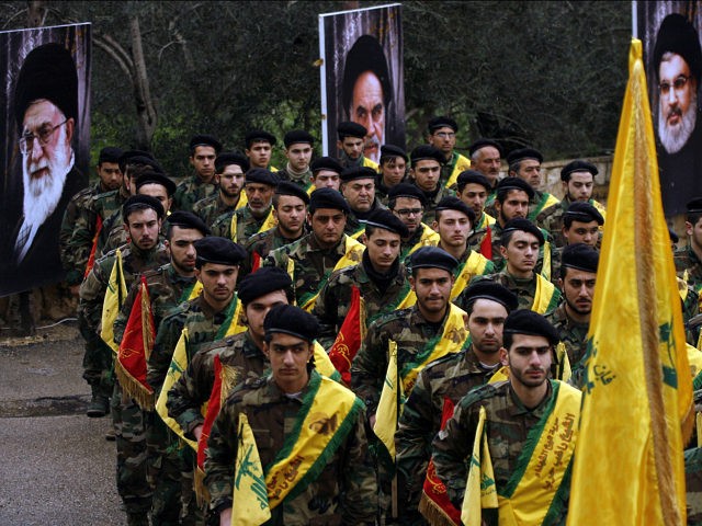 Lebanese Hezbollah fighters march near portraits of Iran's Supreme Leader Ayatollah Ali Kh