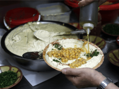 Palestinian restaurant owner Yasser Taha prepares a plate of hummus (R), a paste made from chickpeas, at the Abu Shukri restaurant in the Old City of Jerusalem on September 12, 2015. Palestinians and Israelis are not only in dispute over their land, but also over the paternity of some of …