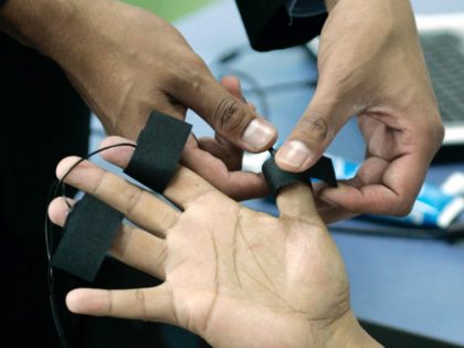 A polygraph examiner applies electrodes on the fingers of a student at the Latin American