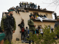 ofra Israeli security forces stand guard as youths supporters of settlements sit on the rooftop of a house which is due to be emptied and demolished in the settlement of Ofra in the occupied West Bank, during an operation by Israeli forces to evict the houses, on February 28, 2017. Nine …