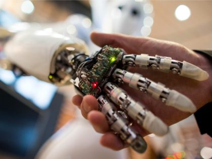 A visitor holds a hand of AILA, or Artificial Intelligence Lightweight Android, during a d