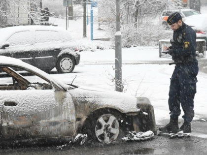 A policeman investigates a burned out car in the suburb Rinkeby, outside Stockholm, on February 21, 2017. Several cars was set in to fire after a riot in Rinkeby. The turmoil started when the police was going to arrest a man in the area. They where attacked with stones and …