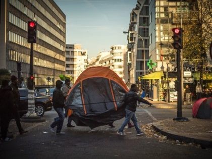 TOPSHOT - Migrants carry a tent across a migrant tent camp in Paris on November 3, 2016, near to the Stalingrad metro station, one of several camps sprouting up around the French capital. Less than 300 kilometres from the recently-demolished "Jungle" migrant camp in Calais, around 2,000 migrants are living …