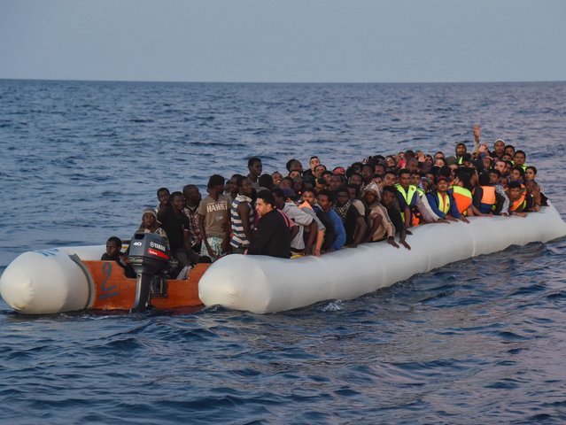 Migrants and refugees sit on a rubber boat before to be rescued by the ship Topaz Responde