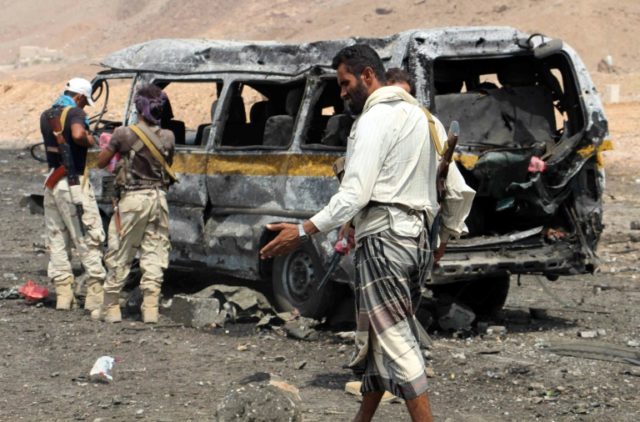 Yemeni soldiers check the scene of a car bomb attack at an army checkpoint in Hajr, a form