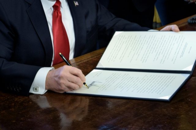 US President Donald Trump signs an executive order directing the Treasury Secretary to rev