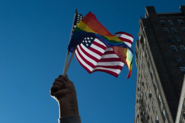 People hold signs and flags at a rally in front of the Stonewall Inn in solidarity with im
