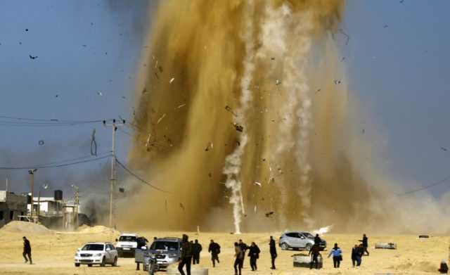 Palestinians run for cover as smoke rises following an Israeli air strike on a Hamas post,