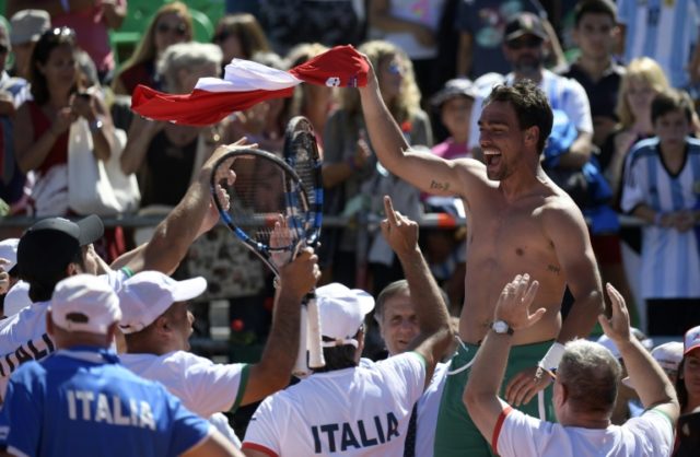 Italy's tennis player Fabio Fognini waves his jersey celebrating with teammates after defe