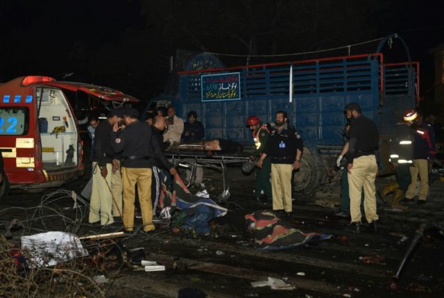 Pakistani policemen and volunteers move the bodies of victims at the site of a bomb explos